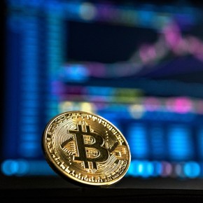 Bitcoin-Münze vor einem verschwommenen Bildschirm